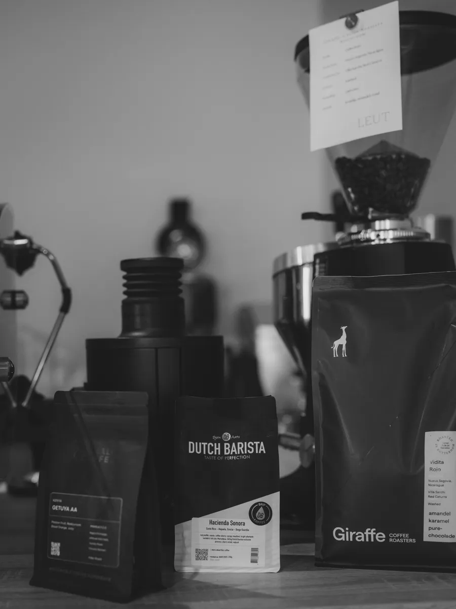 Black and white photo of printed coffee bags beside a café grinder