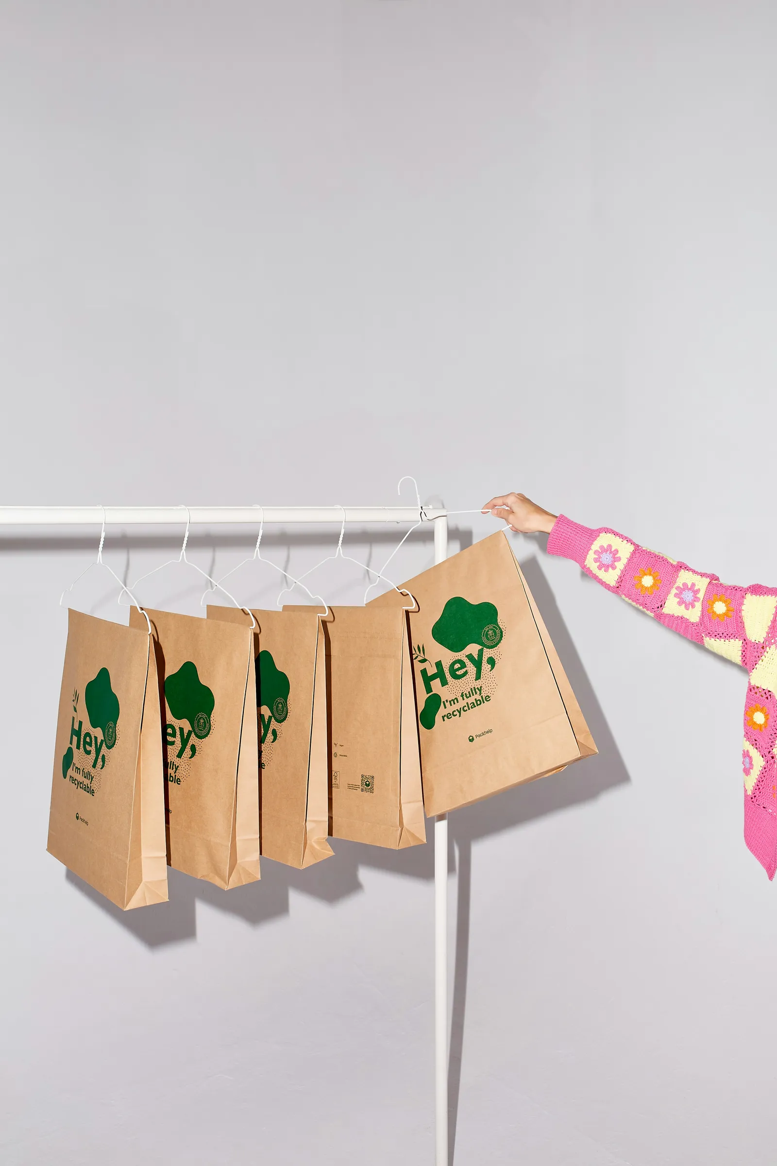 Kraft paper shopping bags with a green print hanging on a rail