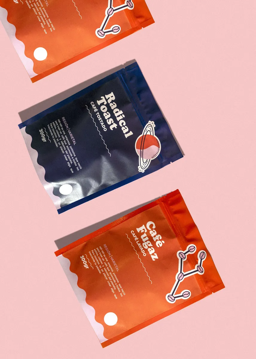 Three printed stand-up coffee pouches in navy and orange on a pink background