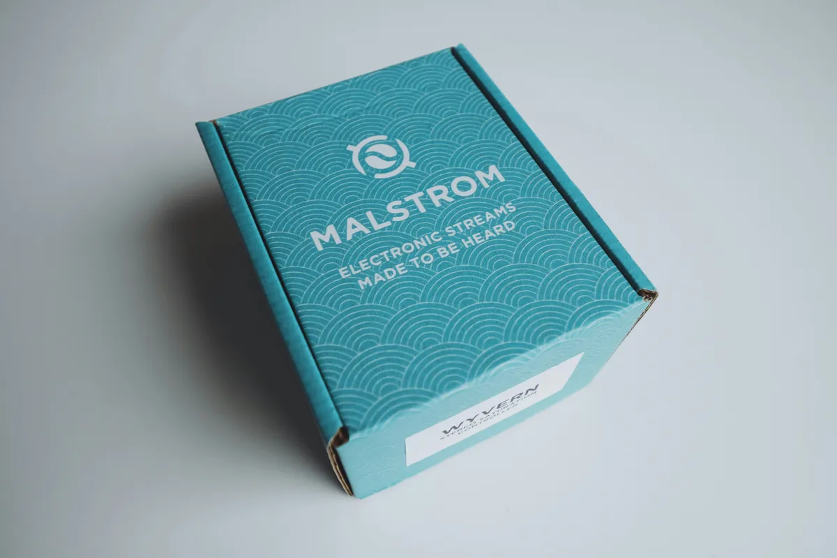 Teal printed mailer box with a wave pattern and a white address label